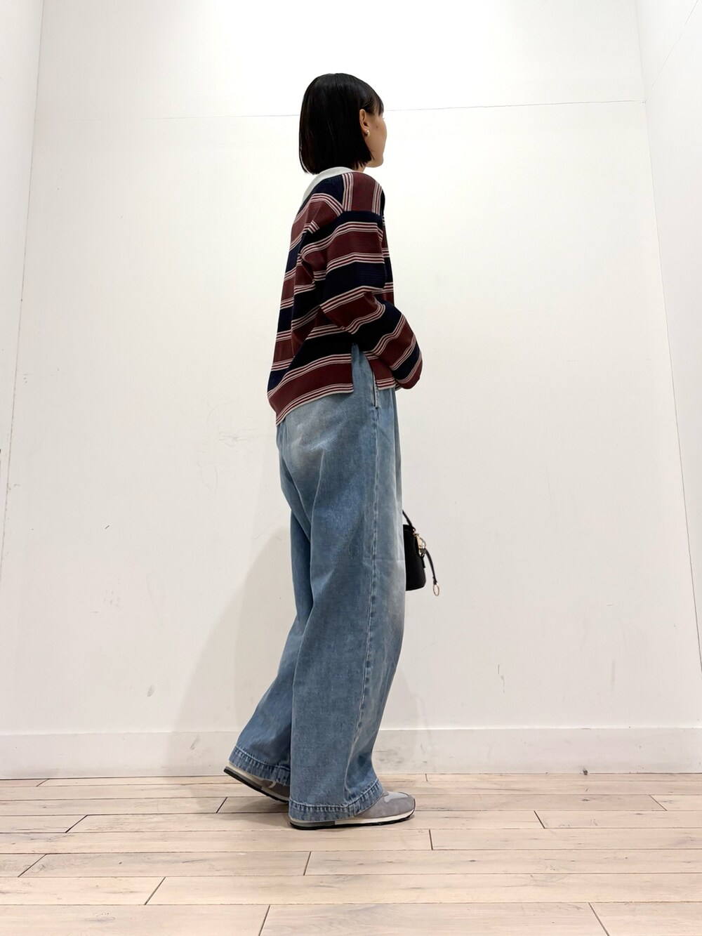 ブルー系のニット/セーター、ブルー系のデニムパンツ、ブラック系のショルダーバッグを着用したレディースの秋コーディネートの5枚目の写真