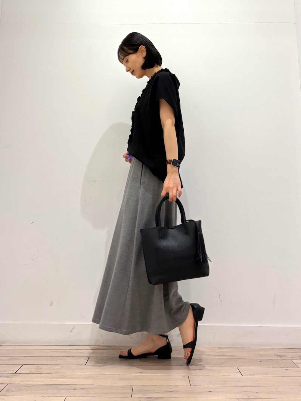 ブラック系のシャツ/ブラウス、グレー系のスカート、ブラック系のサンダルを着用したレディースの夏コーディネートの3枚目の写真
