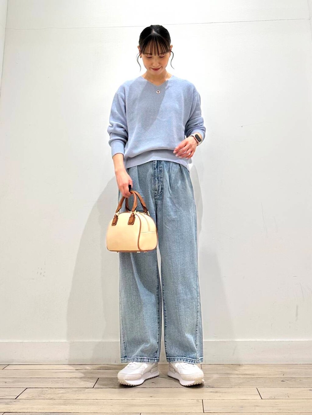 ブルー系のデニムパンツ、ベージュ系のその他アウター、イエロー系のボストンバッグを着用したレディースの冬コーディネートの5枚目の写真