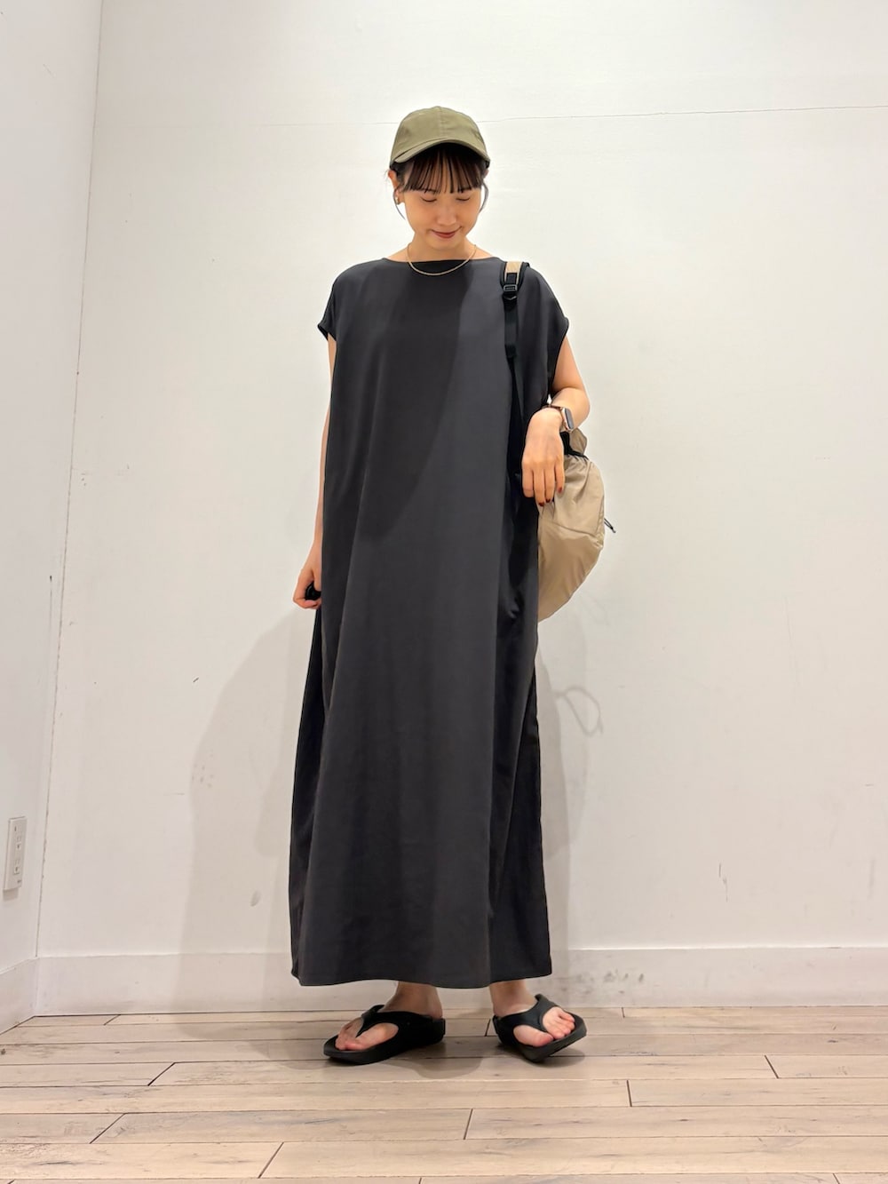 グレー系のワンピース、ベージュ系のバックパック/リュック、ブラック系のサンダルを着用したレディースの夏コーディネートの3枚目の写真