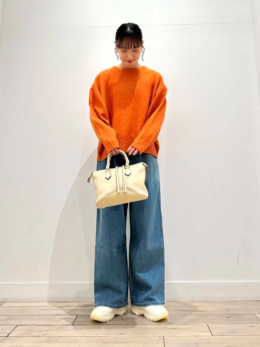 ホワイト系のスニーカー、オレンジ系のニット/セーター、ホワイト系のボストンバッグを着用したレディースの冬コーディネートの2枚目の写真