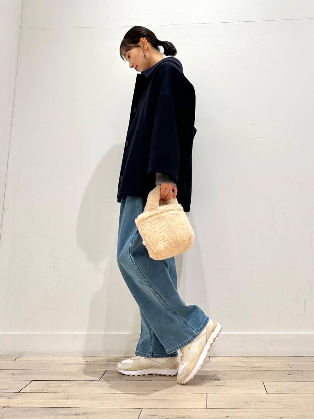 ホワイト系のスニーカー、ブルー系のその他アウター、ベージュ系のハンドバッグを着用したレディースの冬コーディネートの2枚目の写真