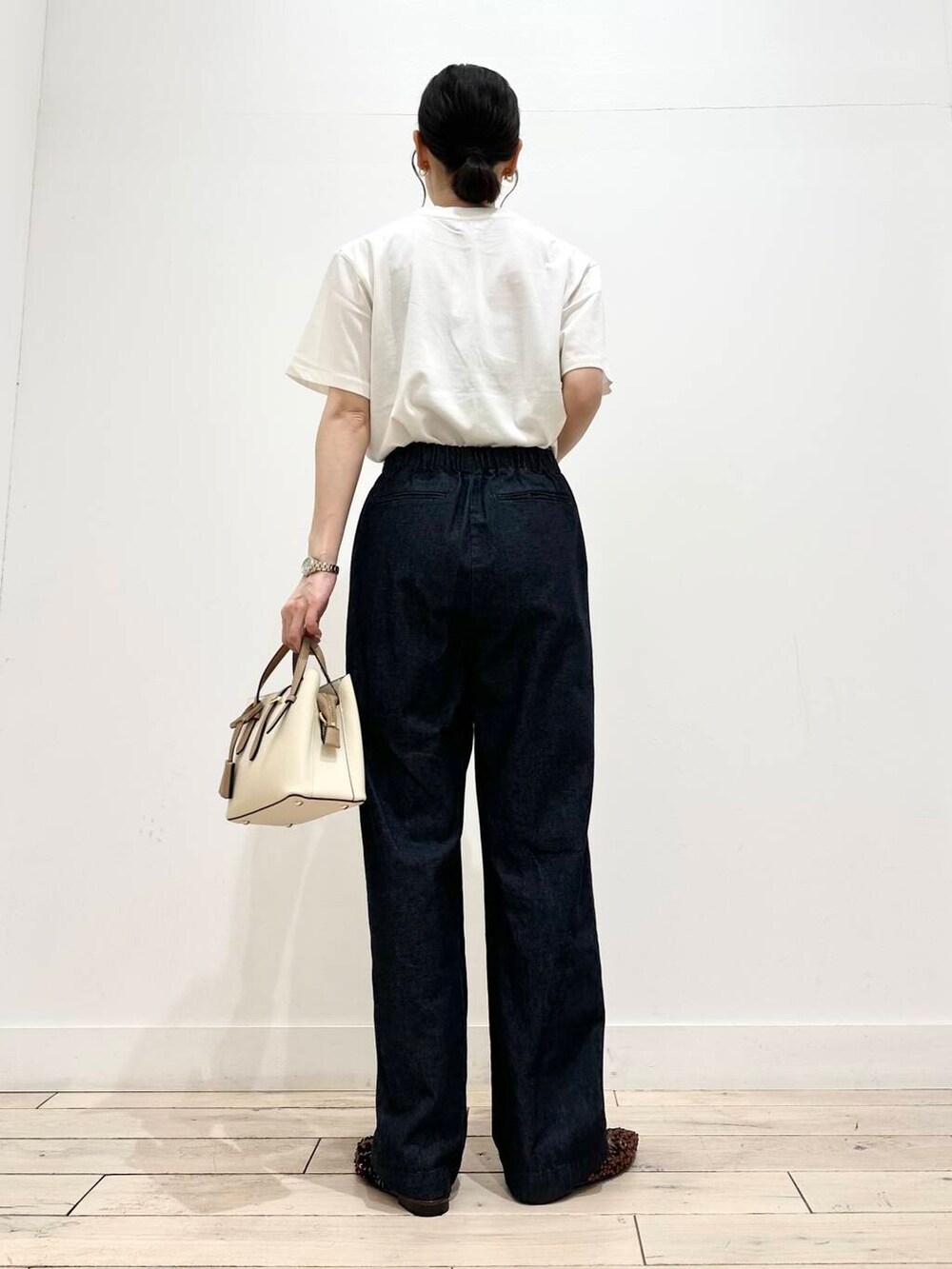 ホワイト系のハンドバッグ、ホワイト系のTシャツ/カットソー、ブルー系のデニムパンツを着用したレディースの夏コーディネートの3枚目の写真