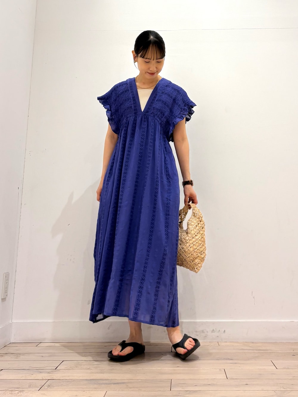 ブルー系のワンピース、ベージュ系のハンドバッグ、ブラック系のサンダルを着用したレディースの夏コーディネートの3枚目の写真