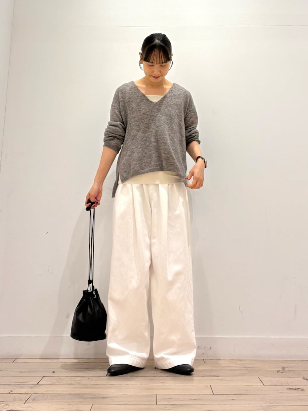 グレー系のニット/セーター、ホワイト系のその他パンツ、ブラック系のショルダーバッグを着用したレディースの秋コーディネートの2枚目の写真