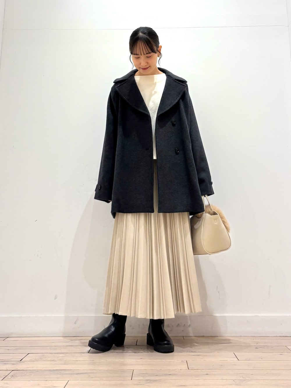 ホワイト系のTシャツ/カットソー、グレー系のピーコート、ブラック系のブーツを着用したレディースの冬コーディネートの2枚目の写真