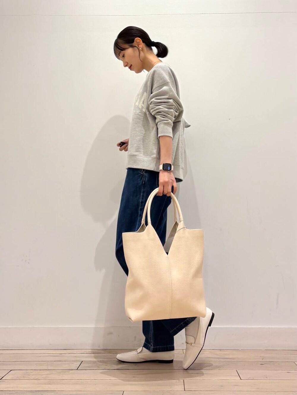 ブルー系のデニムパンツ、ブラック系のマウンテンパーカー、ホワイト系のローファーを着用したレディースの春コーディネートの6枚目の写真