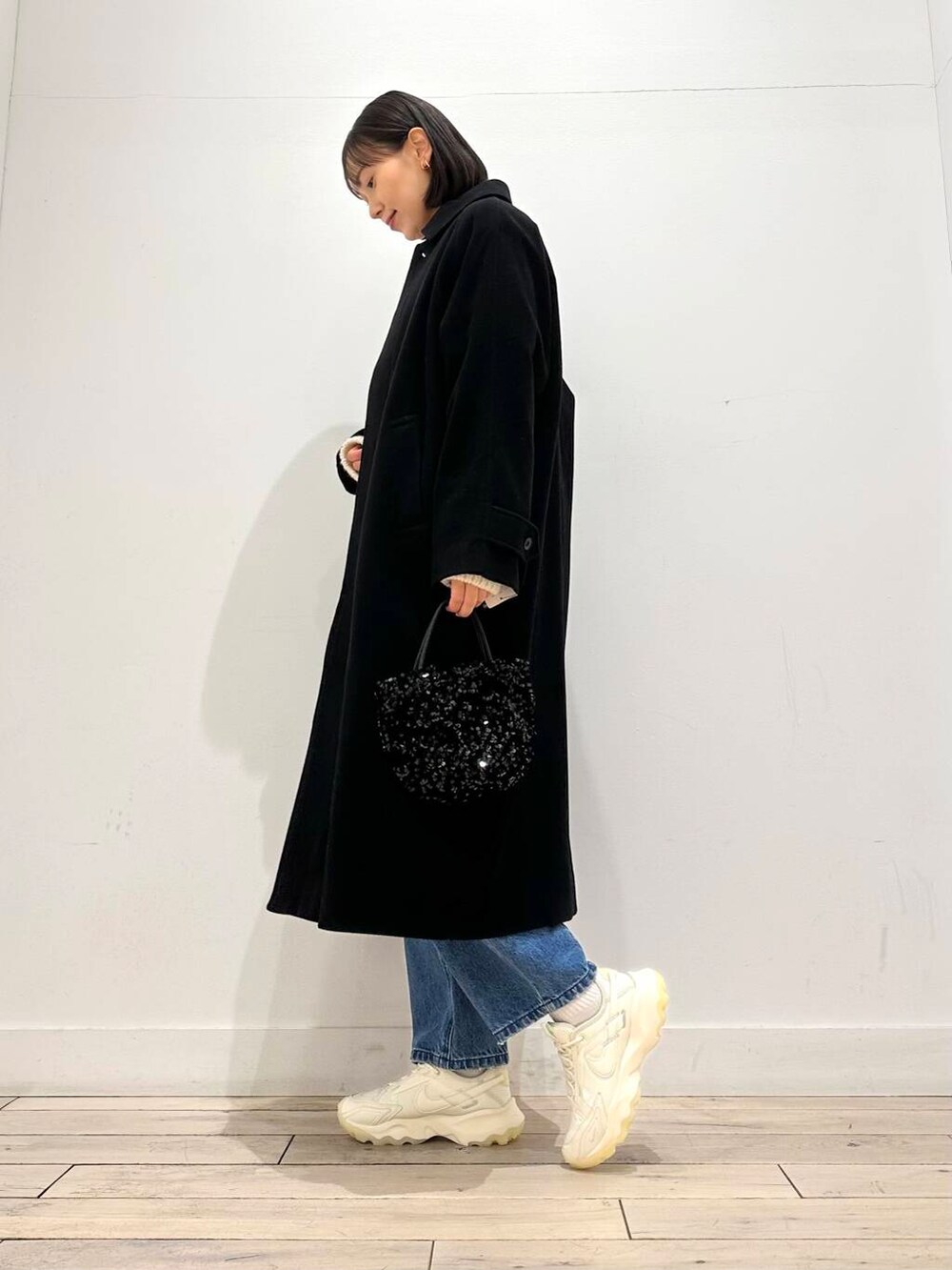 ブラック系のショルダーバッグ、ホワイト系のスニーカー、ブラック系のその他アウターを着用したレディースの冬コーディネートの6枚目の写真