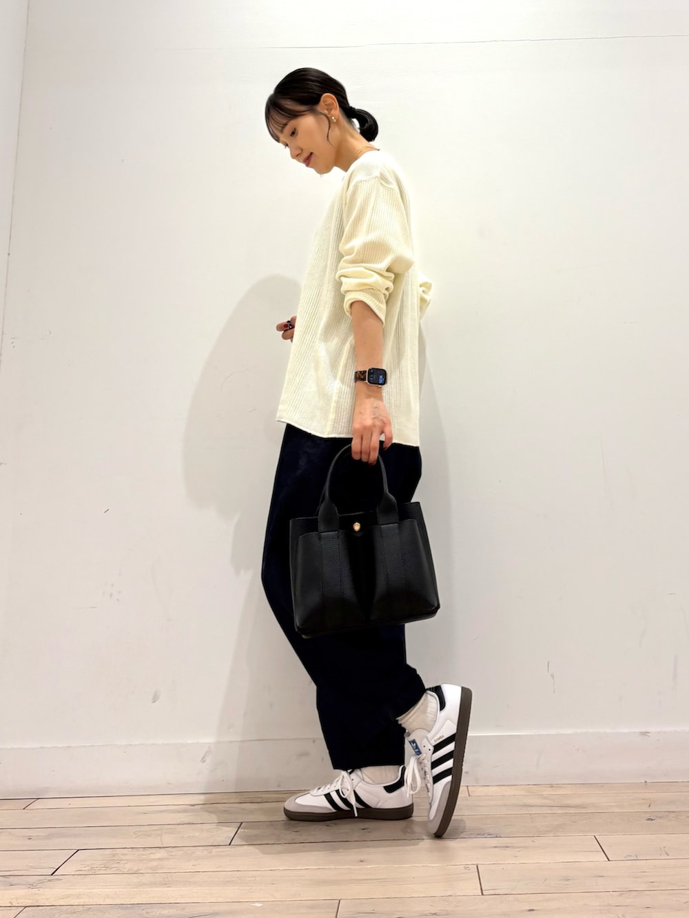 ブルー系のデニムパンツ、ホワイト系のスニーカー、ブラック系のトートバッグを着用したレディースの秋コーディネートの2枚目の写真