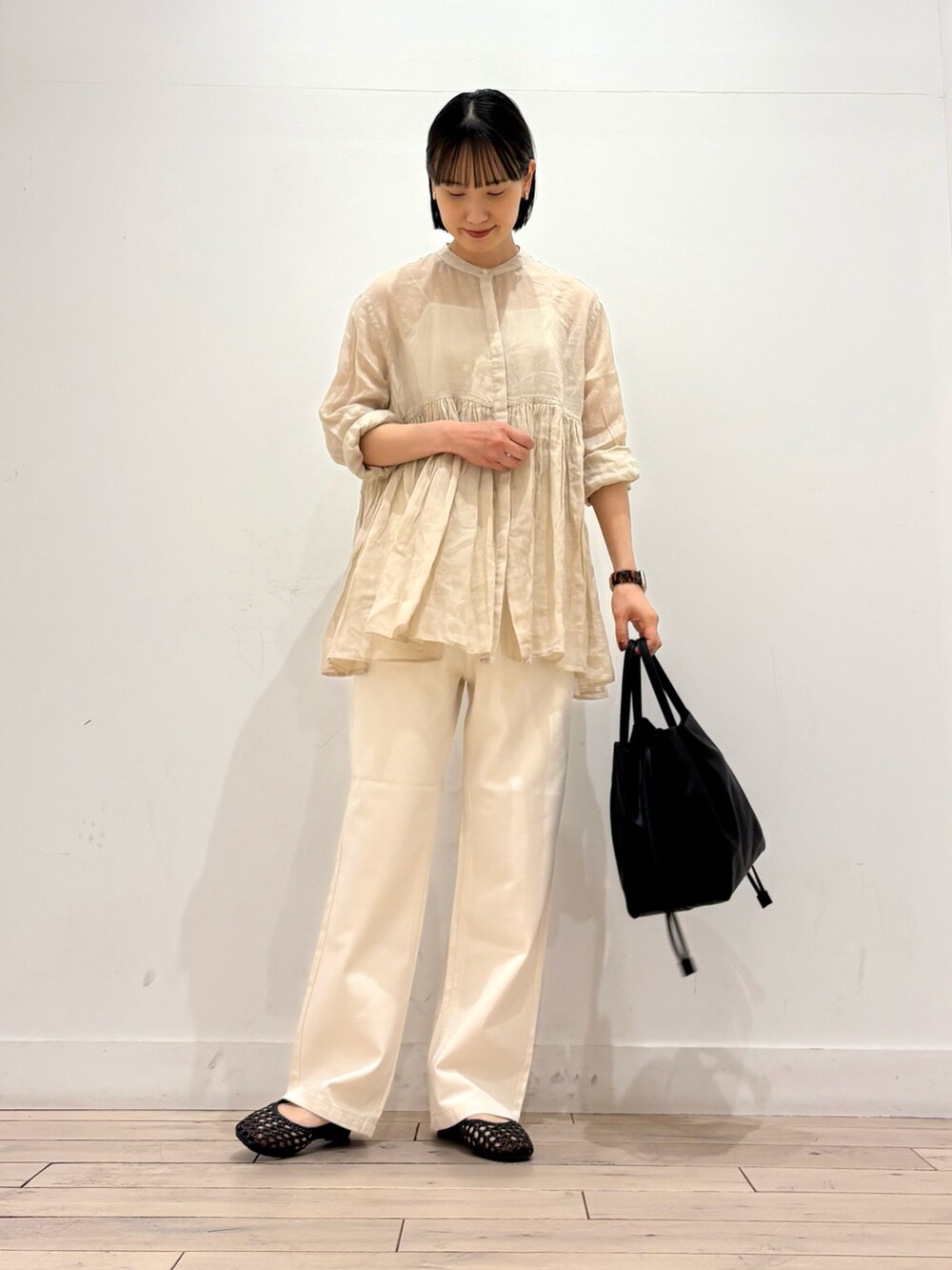ベージュ系のシャツ/ブラウス、ベージュ系のデニムパンツ、ブラック系のショルダーバッグを着用したレディースの春コーディネートの2枚目の写真