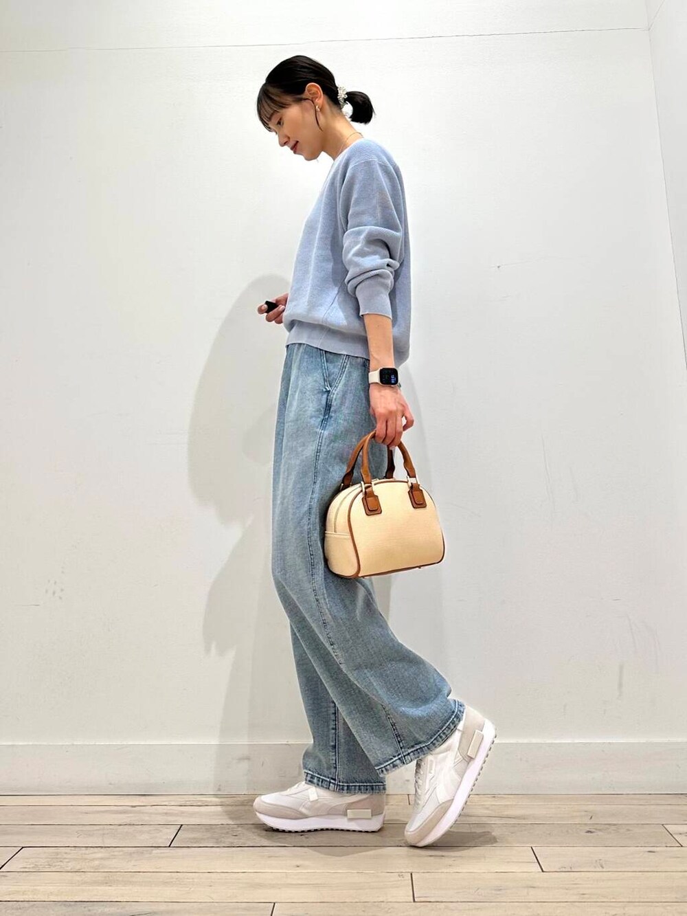 ブルー系のデニムパンツ、ベージュ系のその他アウター、イエロー系のボストンバッグを着用したレディースの冬コーディネートの6枚目の写真