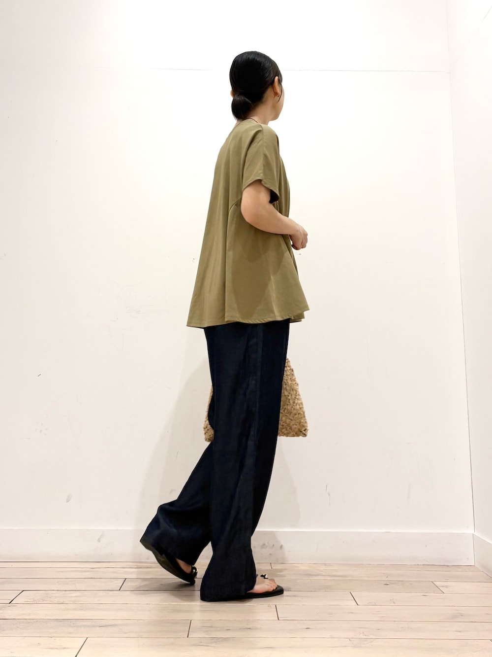 ブルー系のデニムパンツ、ベージュ系のハンドバッグ、ブラック系のサンダルを着用したレディースの夏コーディネートの3枚目の写真