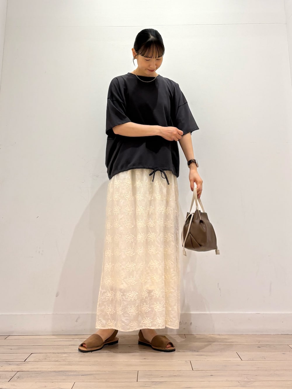 グレー系のTシャツ/カットソー、ホワイト系のスカート、ブラウン系のショルダーバッグを着用したレディースの夏コーディネートの2枚目の写真