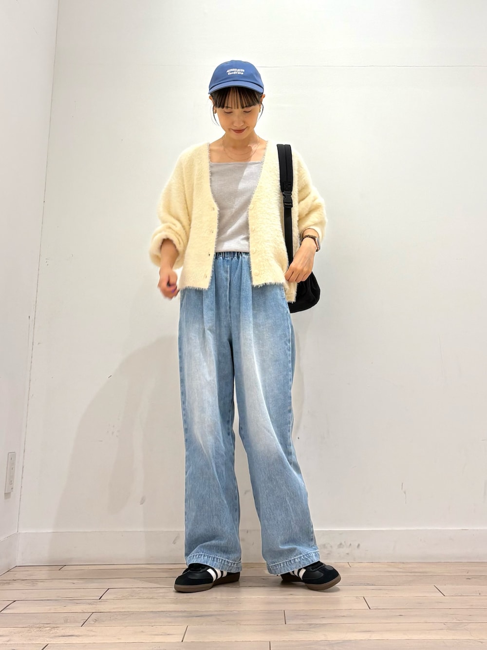 ホワイト系のカーディガン/ボレロ、ブルー系のデニムパンツ、ブラック系のスニーカーを着用したレディースの秋コーディネートの3枚目の写真