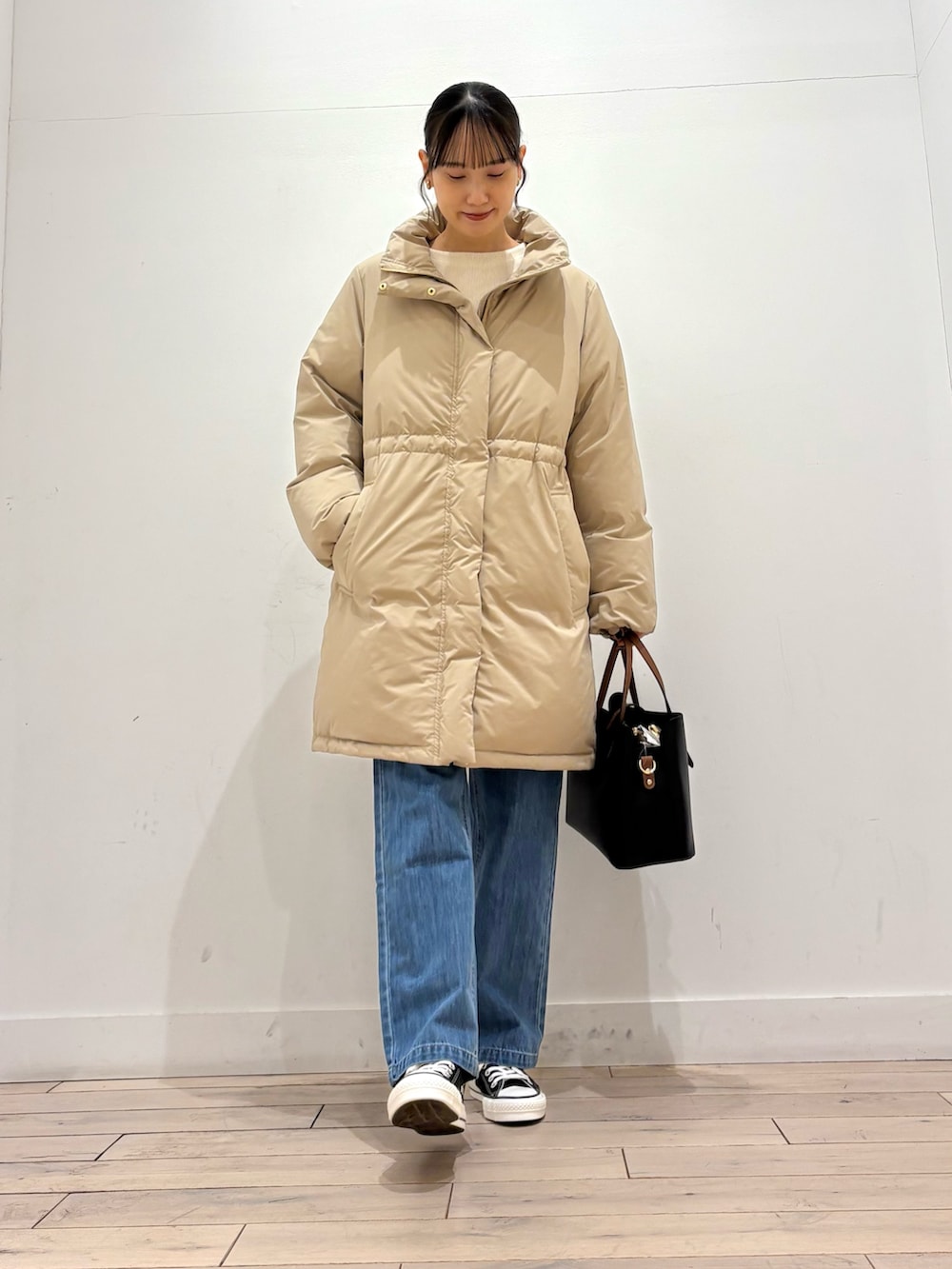 ベージュ系のダウンジャケット/コート、ベージュ系のTシャツ/カットソー、ブルー系のその他パンツを着用したレディースの冬コーディネートの2枚目の写真
