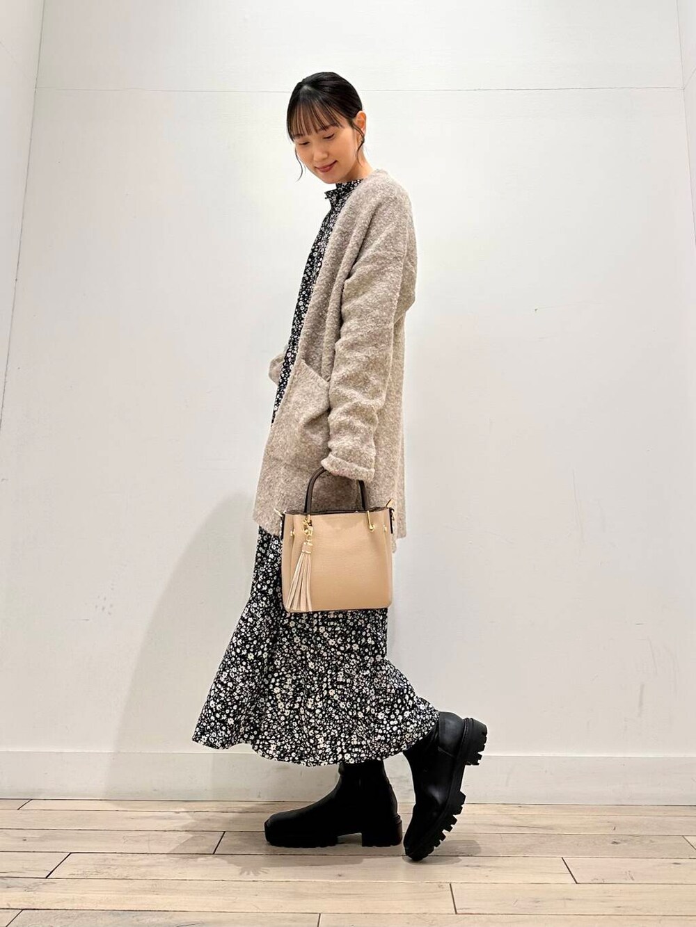 ベージュ系のトートバッグ、ブラック系のブーツ、ベージュ系のカーディガン/ボレロを着用したレディースの冬コーディネートの3枚目の写真