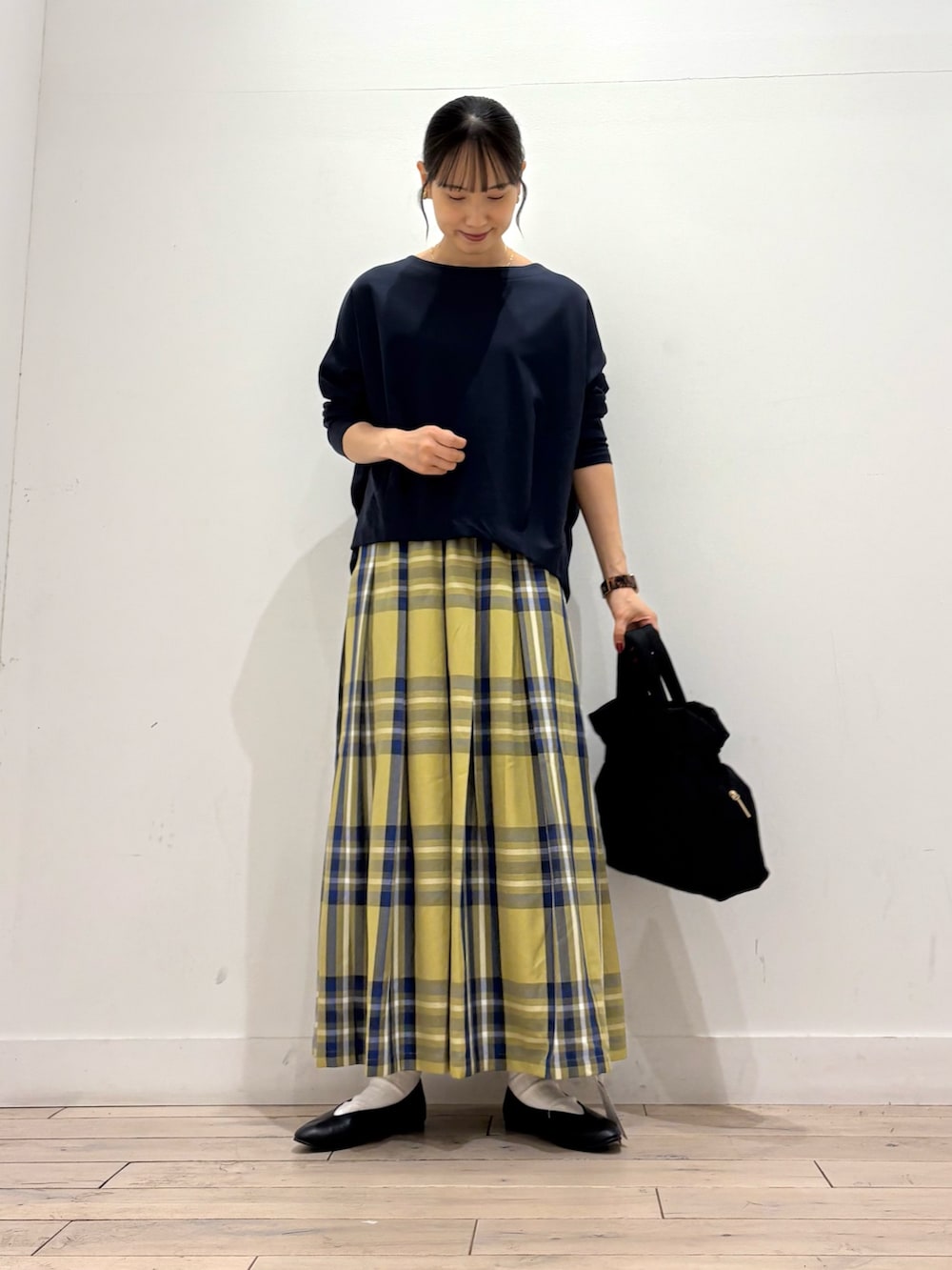 ブルー系のTシャツ/カットソー、イエロー系のスカート、ブラック系のトートバッグを着用したレディースの秋コーディネートの3枚目の写真