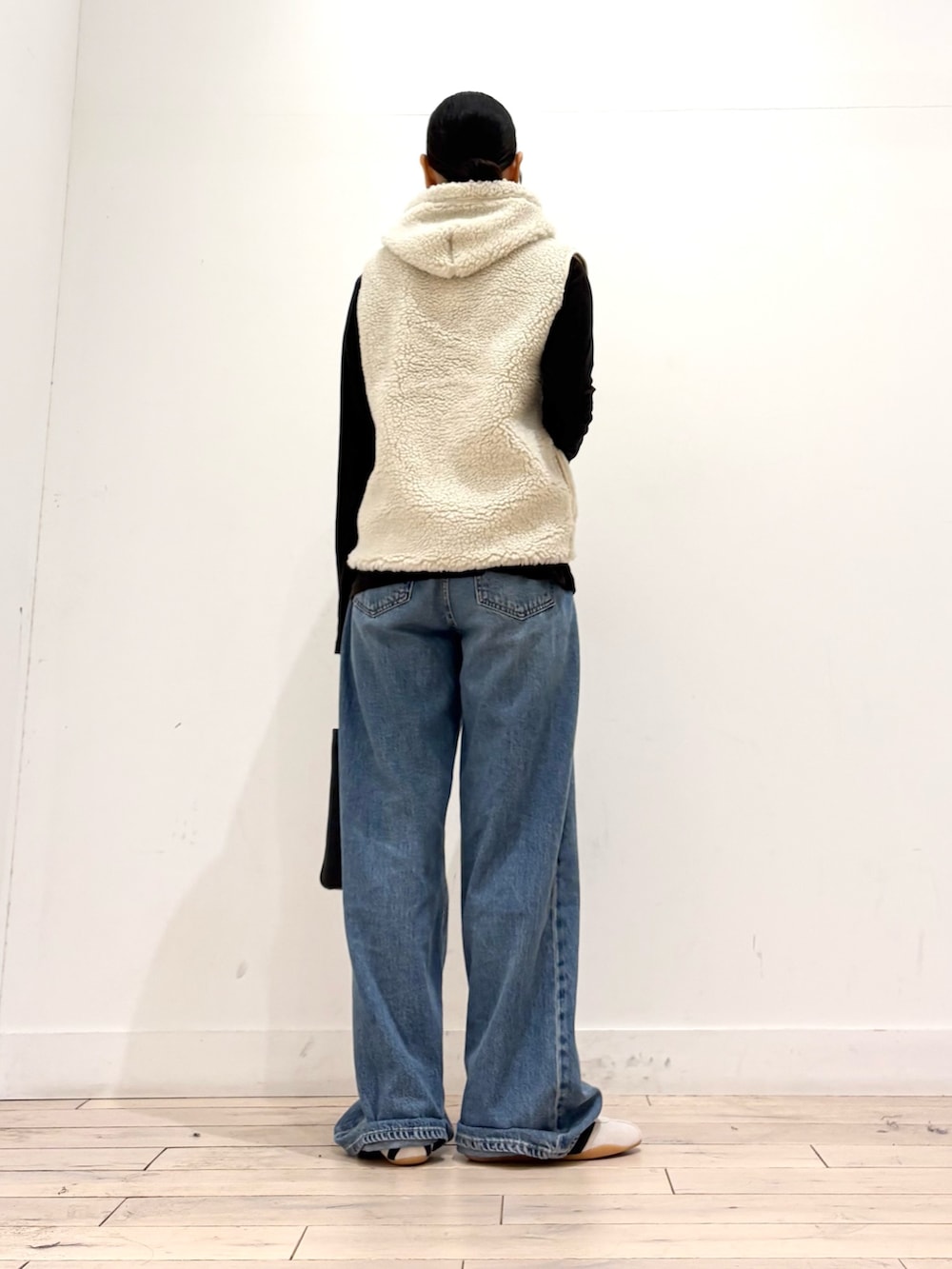 ブラウン系のTシャツ/カットソー、ホワイト系のダウンベスト、ホワイト系のスニーカーを着用したレディースの秋コーディネートの3枚目の写真