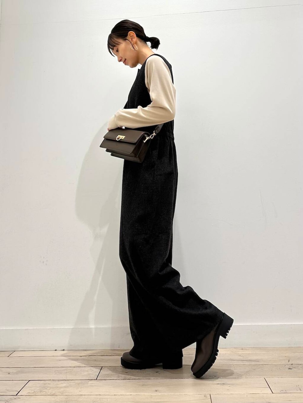 ブラウン系のショルダーバッグ、ブラウン系のブーツ、ベージュ系のTシャツ/カットソーを着用したレディースの秋コーディネートの3枚目の写真