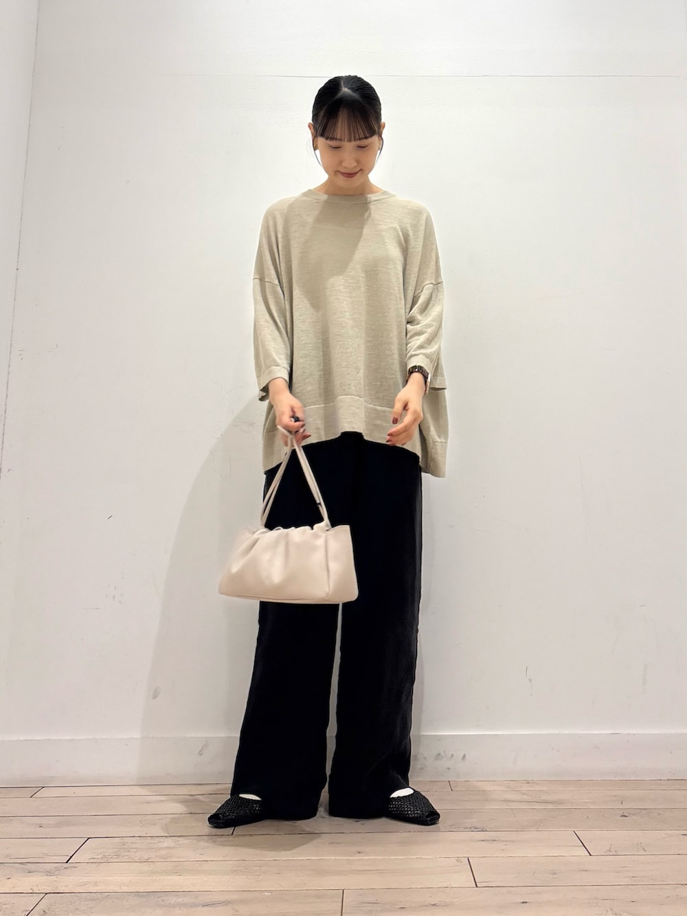 ベージュ系のニット/セーター、ブラック系のその他パンツ、ホワイト系のショルダーバッグを着用したレディースの夏コーディネートの2枚目の写真