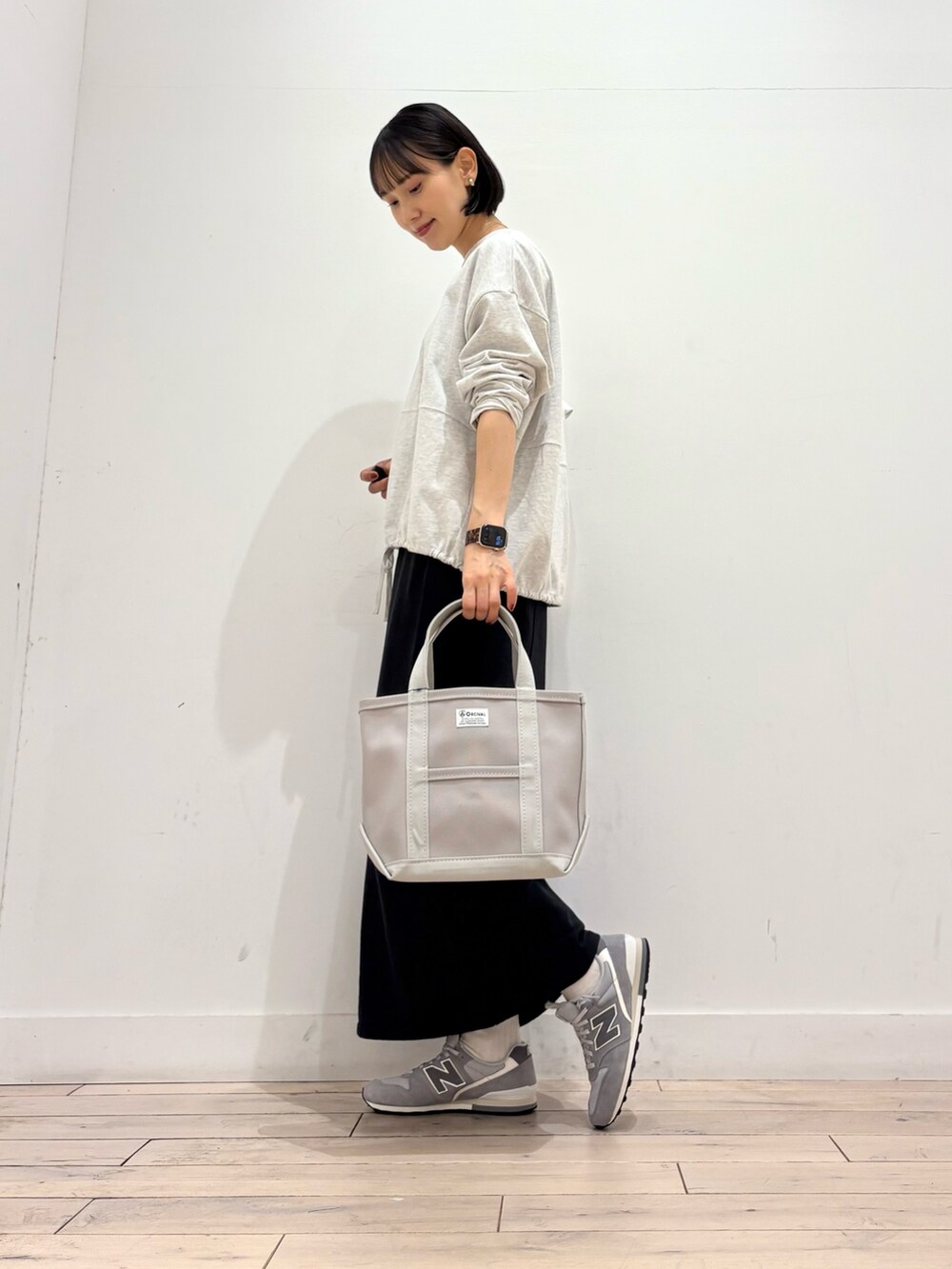 ブラック系のスカート、グレー系のトートバッグ、グレー系のスニーカーを着用したレディースの秋コーディネートの2枚目の写真