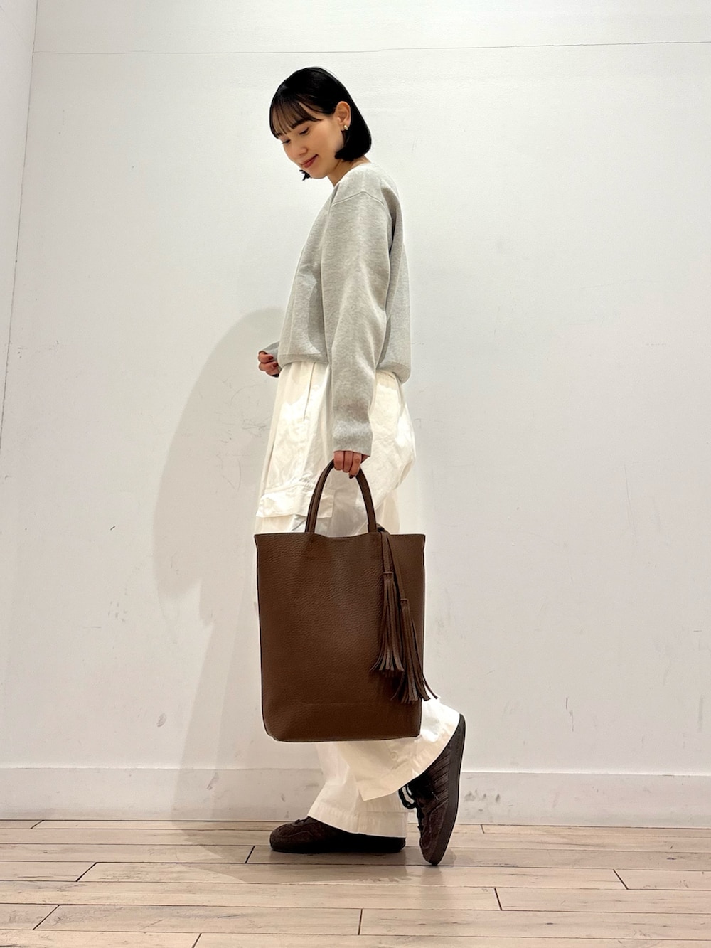 ベージュ系のニット/セーター、ベージュ系のトレンチコート、ブラウン系のトートバッグを着用したレディースの冬コーディネートの6枚目の写真