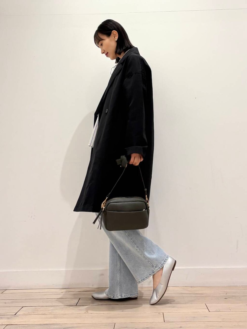 グリーン系のショルダーバッグ、シルバー系のパンプス、ブルー系のデニムパンツを着用したレディースの春コーディネートの7枚目の写真
