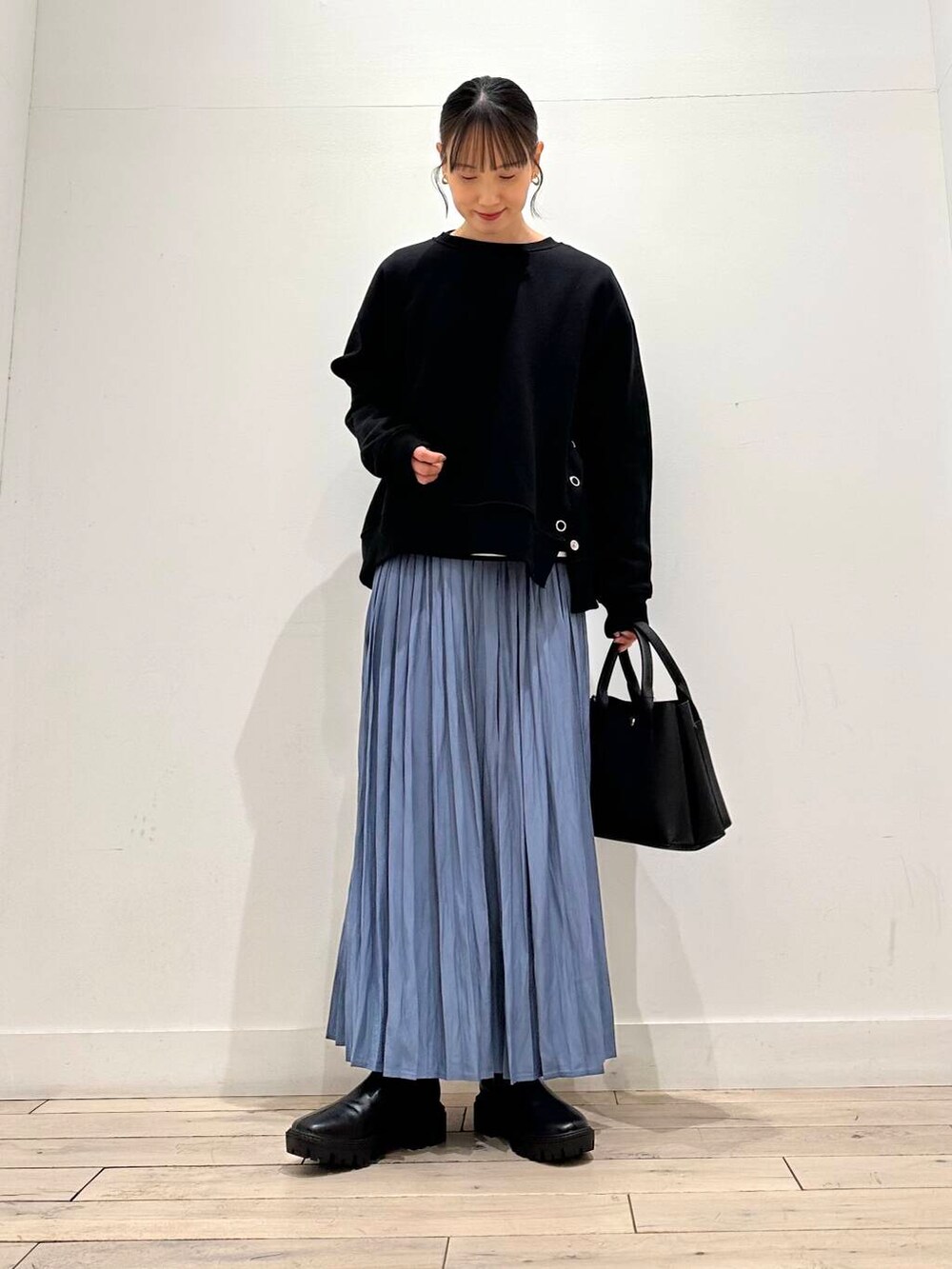 ブラック系のトートバッグ、ホワイト系のTシャツ/カットソー、ブラック系のブーツを着用したレディースの冬コーディネートの2枚目の写真