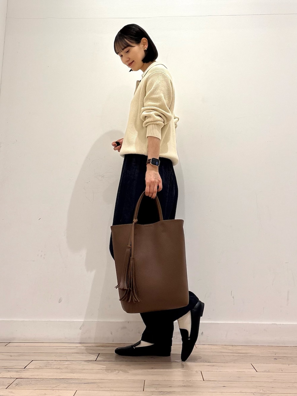 ホワイト系のニット/セーター、ブルー系のデニムパンツ、ブラウン系のトートバッグを着用したレディースの冬コーディネートの2枚目の写真