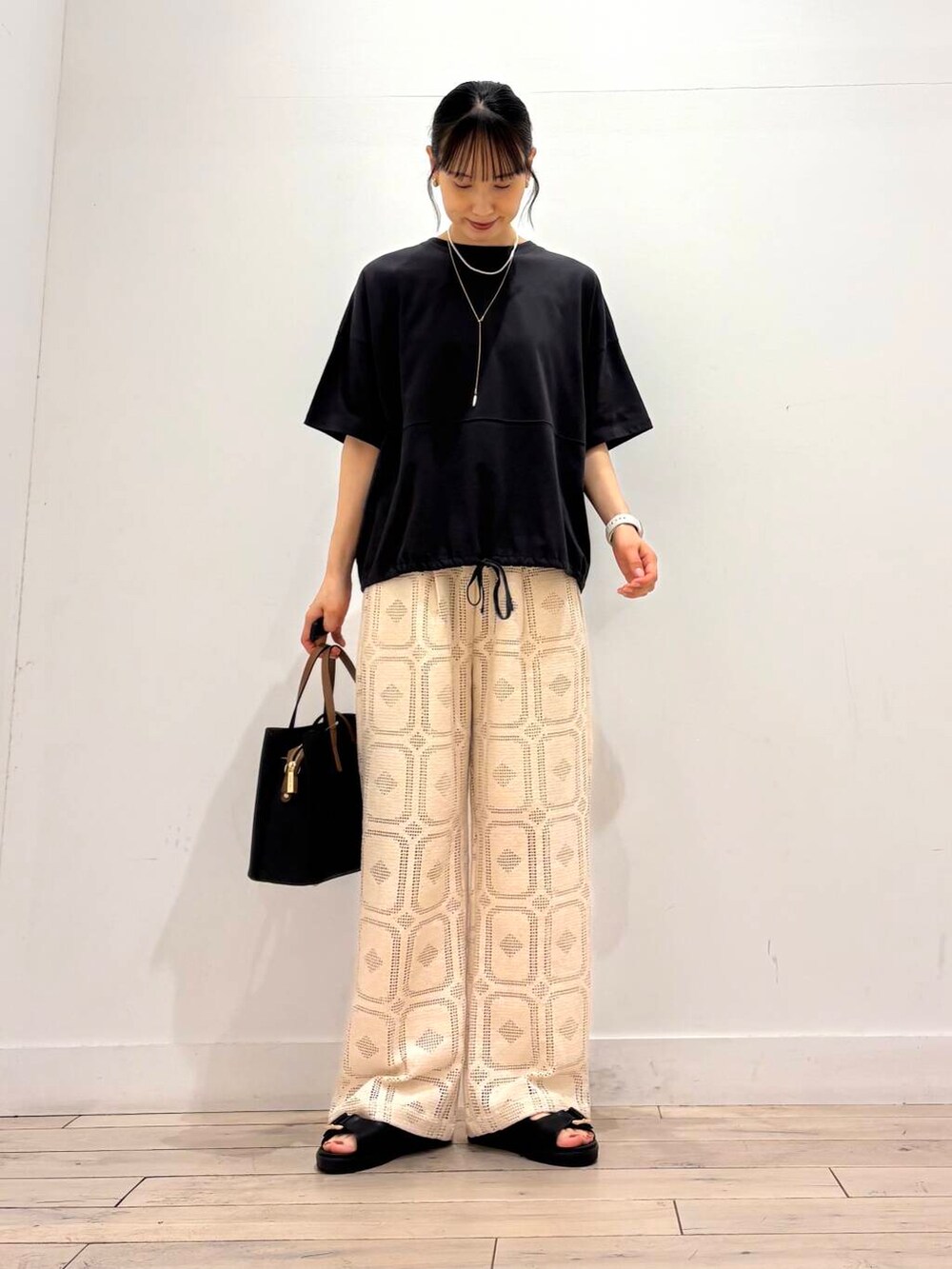 ブラック系のトートバッグ、グレー系のTシャツ/カットソー、ブラック系のサンダルを着用したレディースの夏コーディネートの2枚目の写真