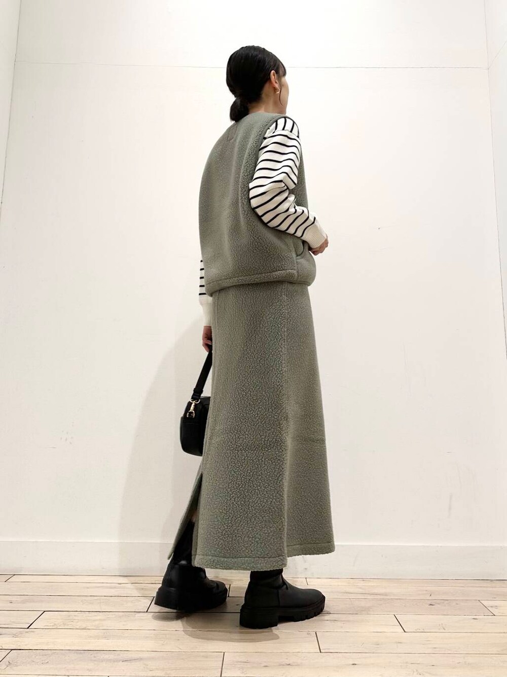 ブラック系のニット/セーター、ブラック系のショルダーバッグ、ブラック系のブーツを着用したレディースの冬コーディネートの4枚目の写真