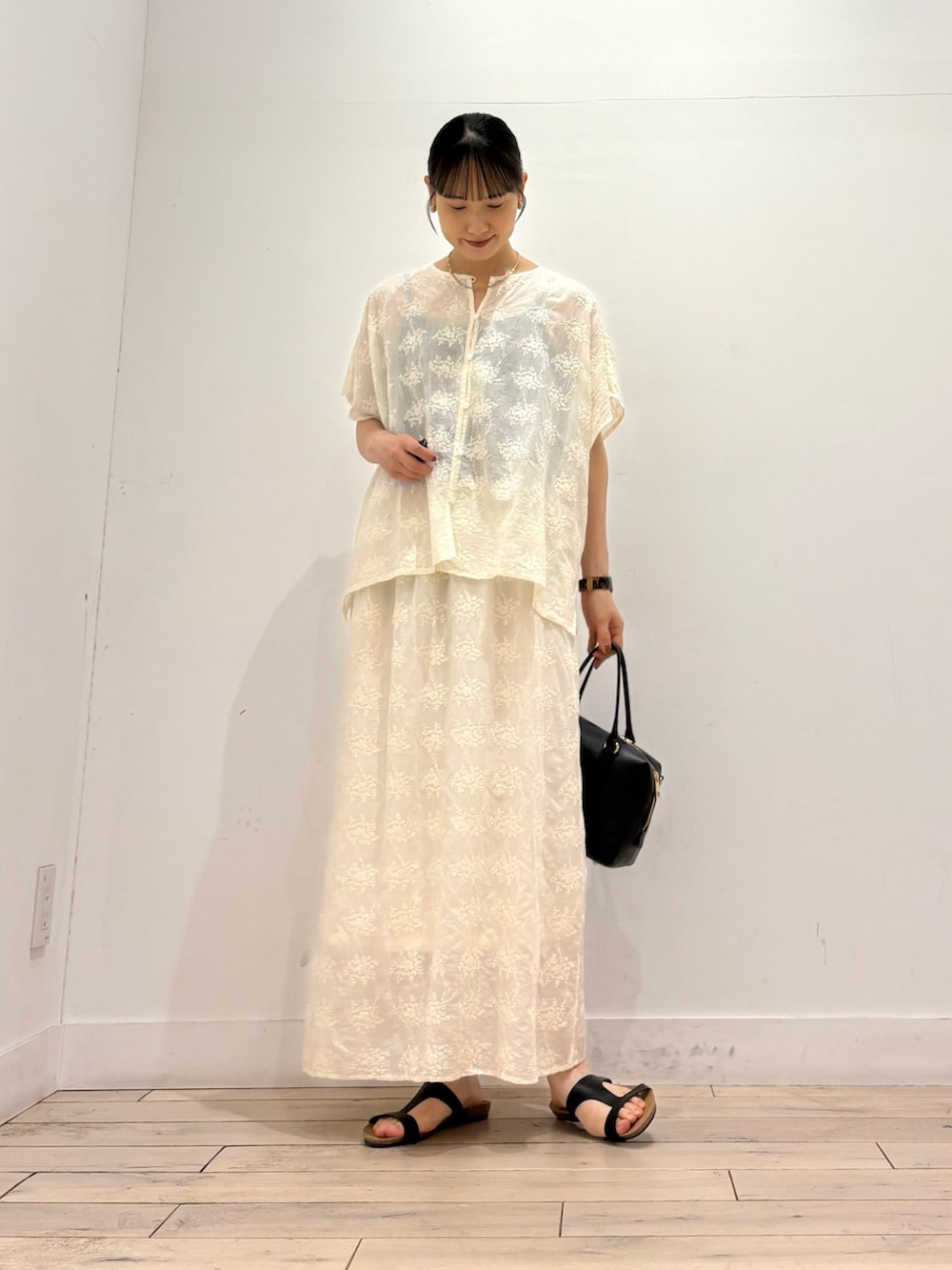 ホワイト系のシャツ/ブラウス、ホワイト系のスカート、ブラック系のサンダルを着用したレディースの夏コーディネートの3枚目の写真