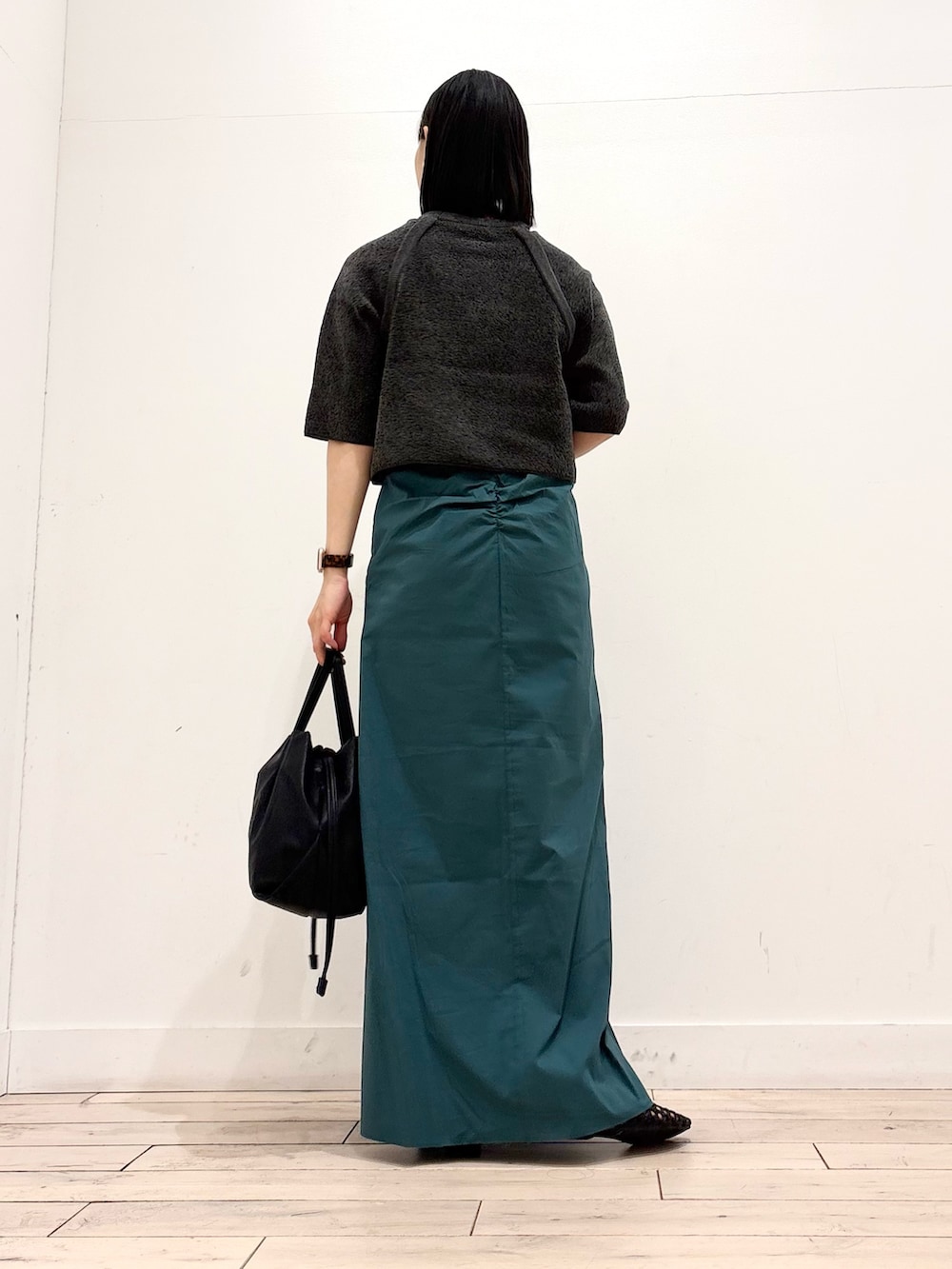 グレー系のニット/セーター、グリーン系のスカート、ブラック系のショルダーバッグを着用したレディースの春コーディネートの5枚目の写真