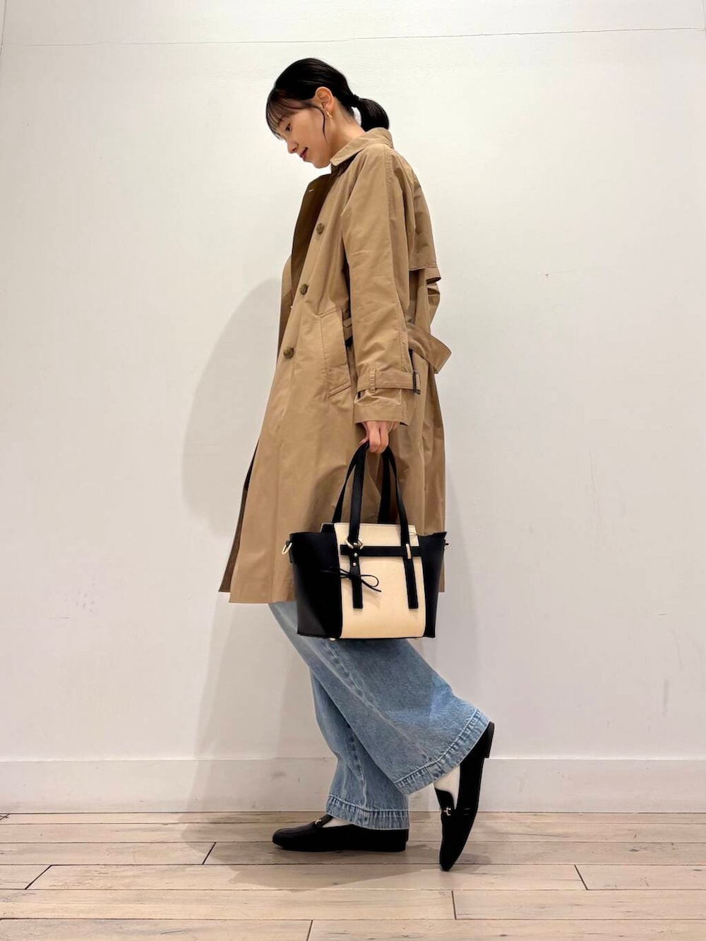 ブルー系のデニムパンツ、ベージュ系のトレンチコート、ブラック系のローファーを着用したレディースの春コーディネートの2枚目の写真