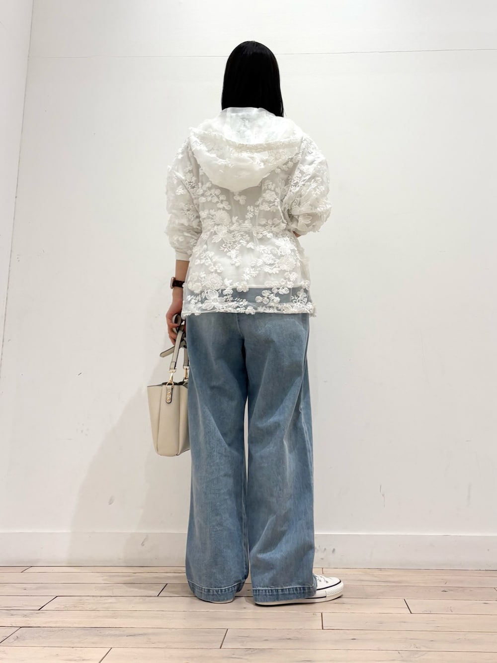 ホワイト系のショルダーバッグ、ホワイト系のスニーカー、ブルー系のデニムパンツを着用したレディースの春コーディネートの5枚目の写真