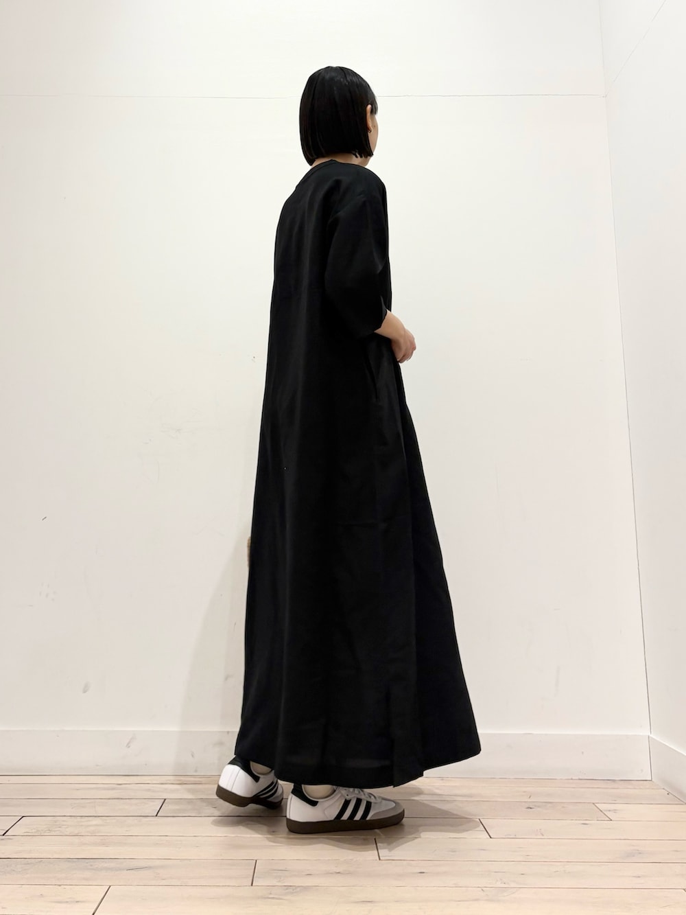 ブラック系のワンピース、ベージュ系のトートバッグ、ホワイト系のスニーカーを着用したレディースの春コーディネートの4枚目の写真