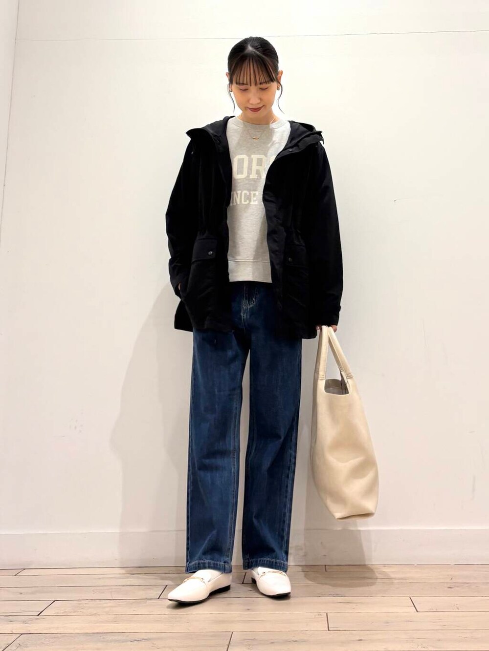 ブルー系のデニムパンツ、ブラック系のマウンテンパーカー、ホワイト系のローファーを着用したレディースの春コーディネートの2枚目の写真