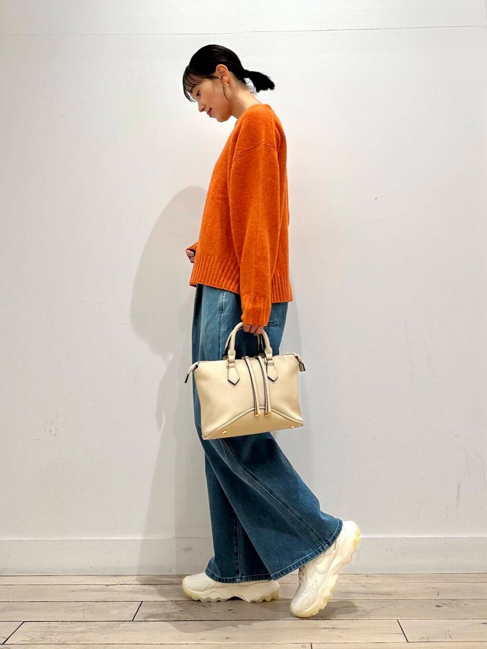 ホワイト系のスニーカー、オレンジ系のニット/セーター、ホワイト系のボストンバッグを着用したレディースの冬コーディネートの4枚目の写真