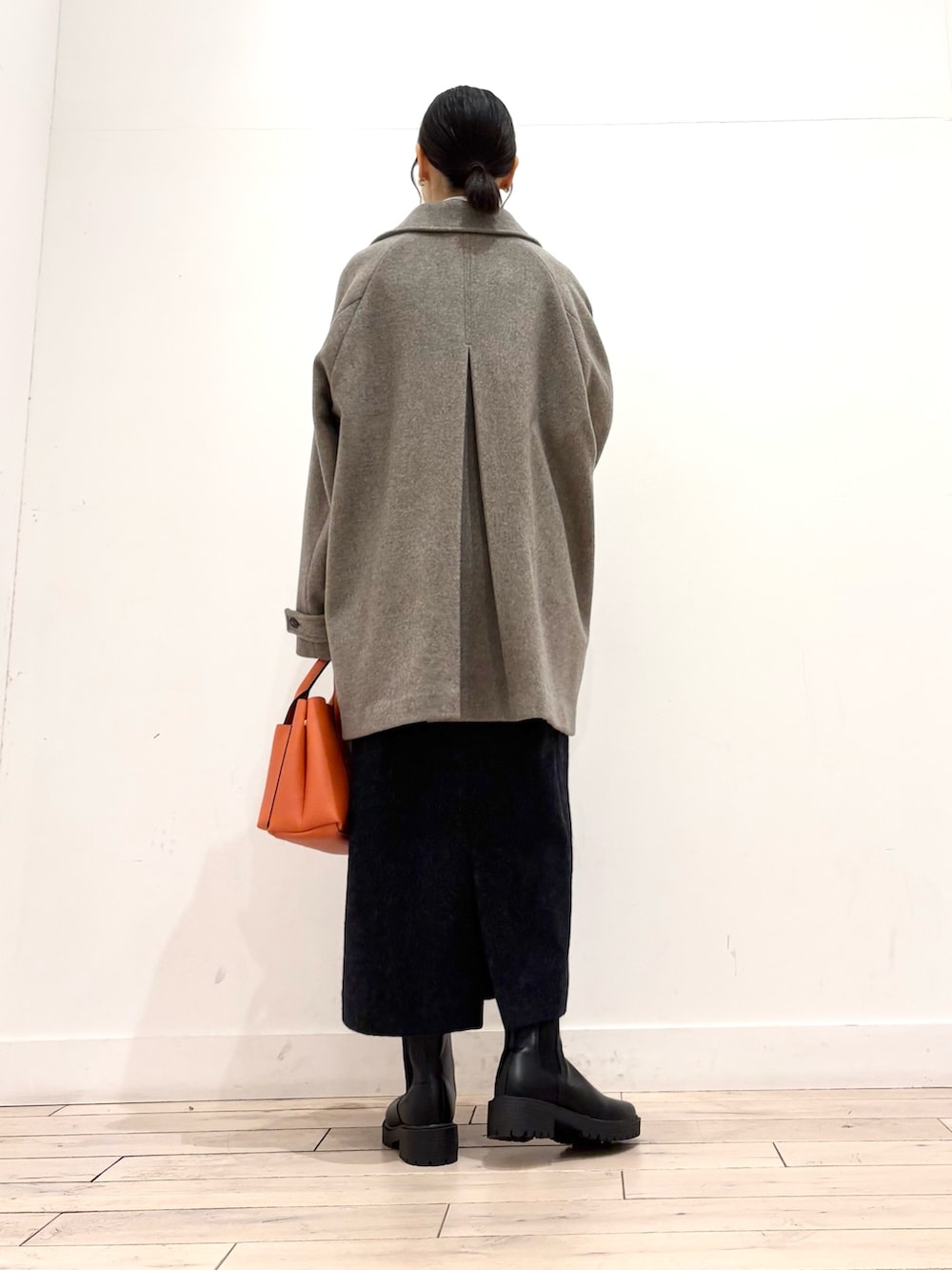 ブラック系のブーツ、オレンジ系のトートバッグ、グレー系のワンピースを着用したレディースの秋コーディネートの3枚目の写真