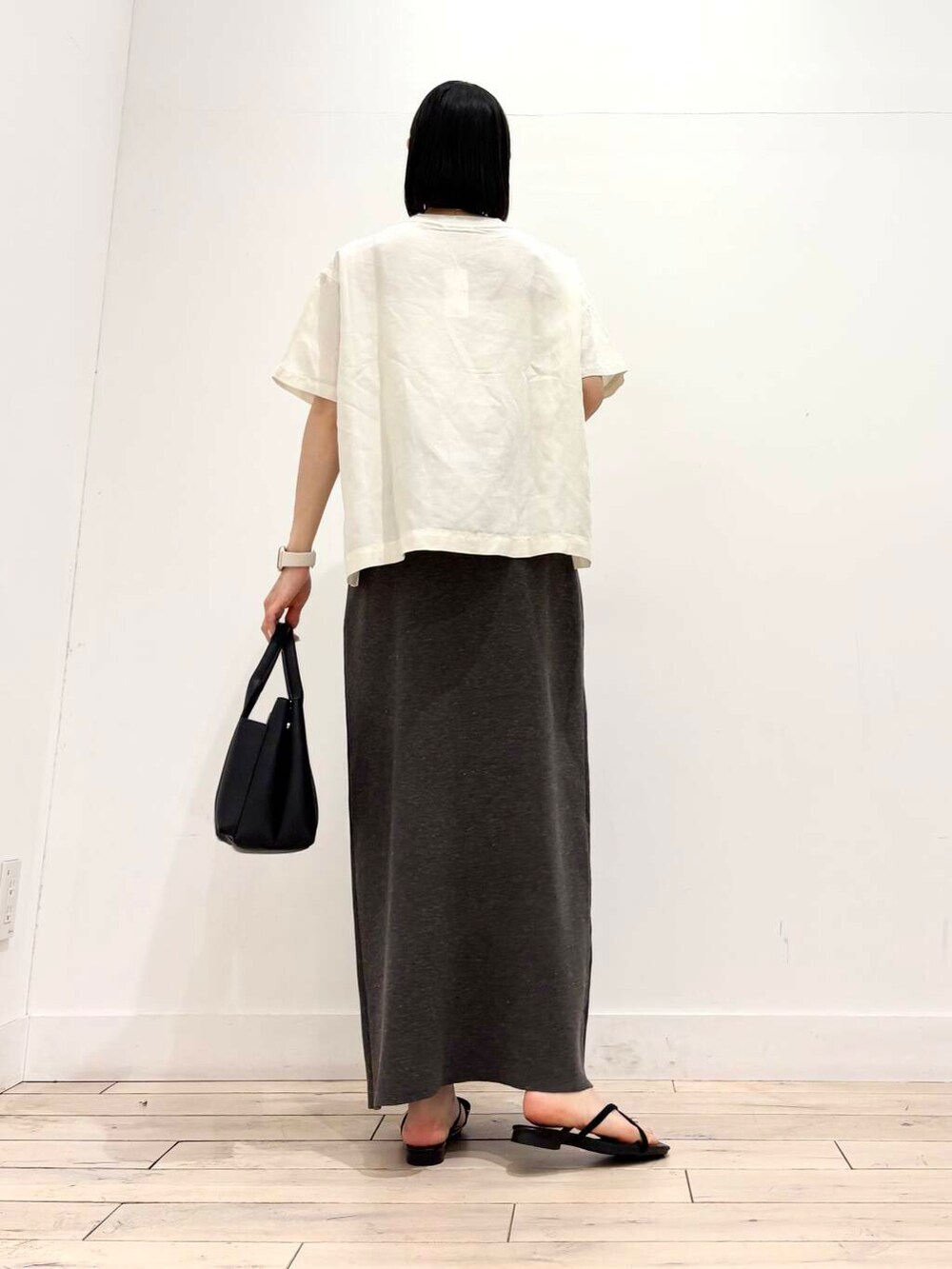 ブラック系のトートバッグ、ホワイト系のシャツ/ブラウス、グレー系のスカートを着用したレディースの夏コーディネートの3枚目の写真