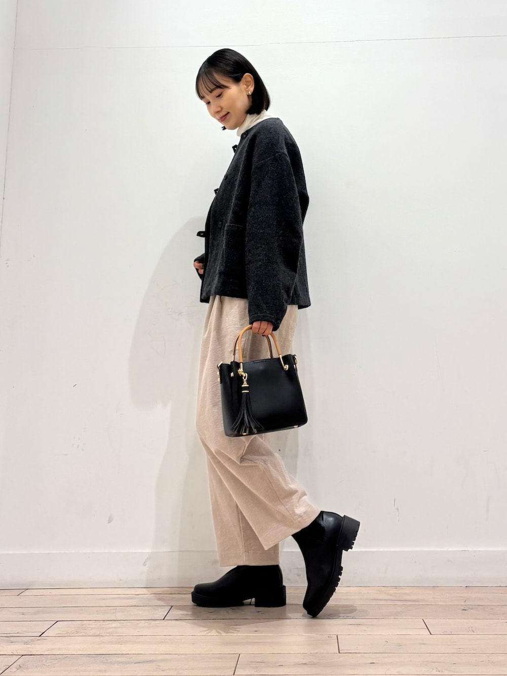 グレー系のノーカラージャケット、ホワイト系のTシャツ/カットソー、ブラック系のブーツを着用したレディースの秋コーディネートの4枚目の写真