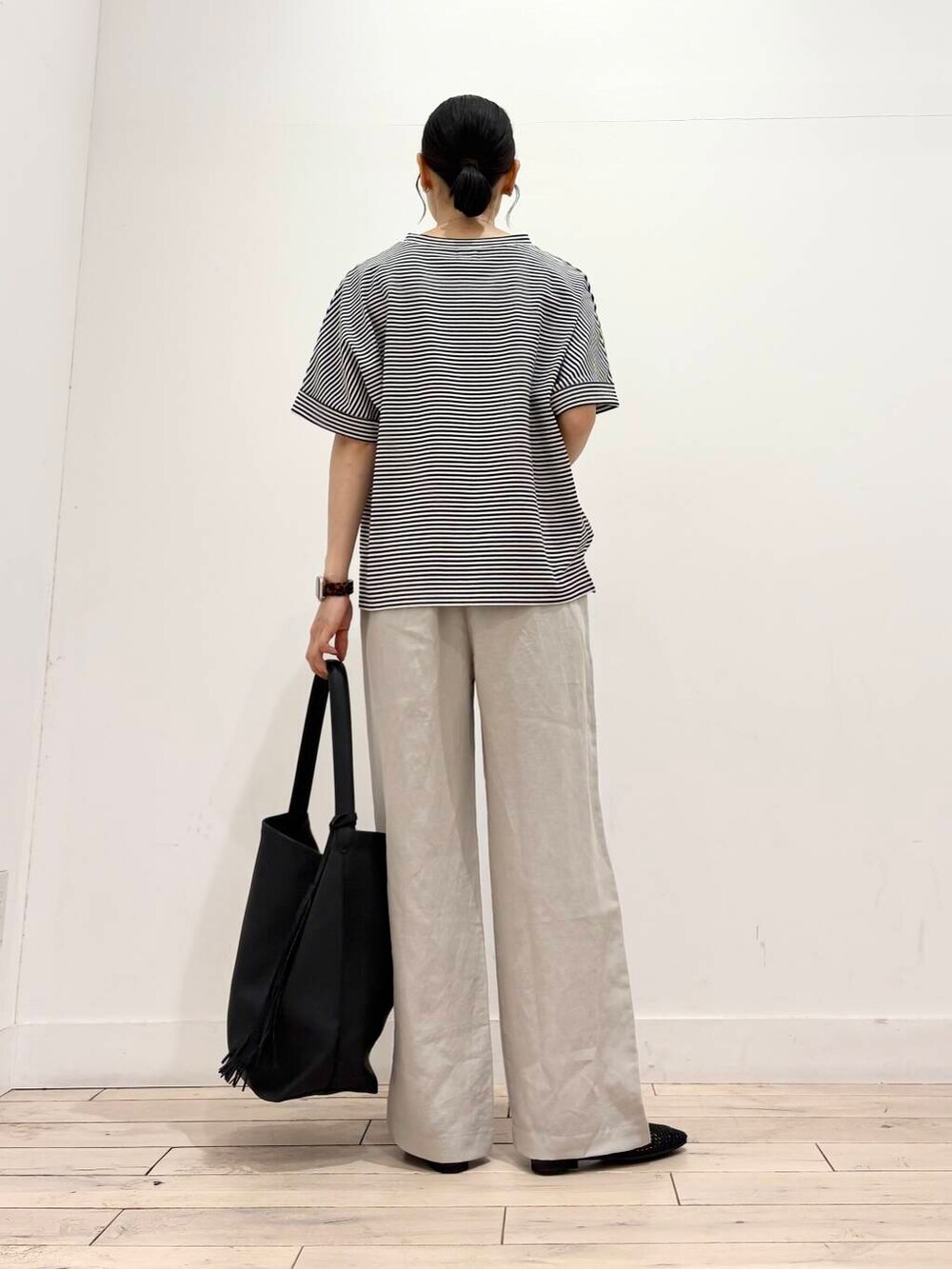 ブラック系のトートバッグ、ブラック系のバレエシューズ、ホワイト系のTシャツ/カットソーを着用したレディースの夏コーディネートの4枚目の写真