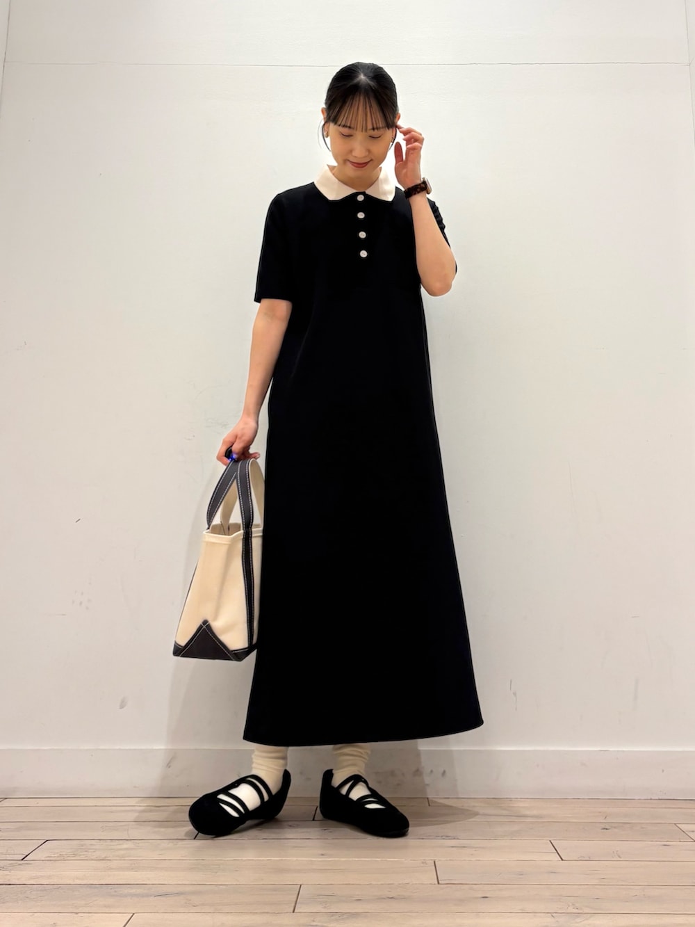 ブラック系のワンピース、グレー系のトートバッグ、ブラック系のスニーカーを着用したレディースの春コーディネートの3枚目の写真