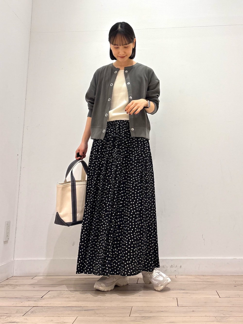 グレー系のカーディガン/ボレロ、グレー系のトートバッグ、ブラック系のスカートを着用したレディースの春コーディネートの2枚目の写真