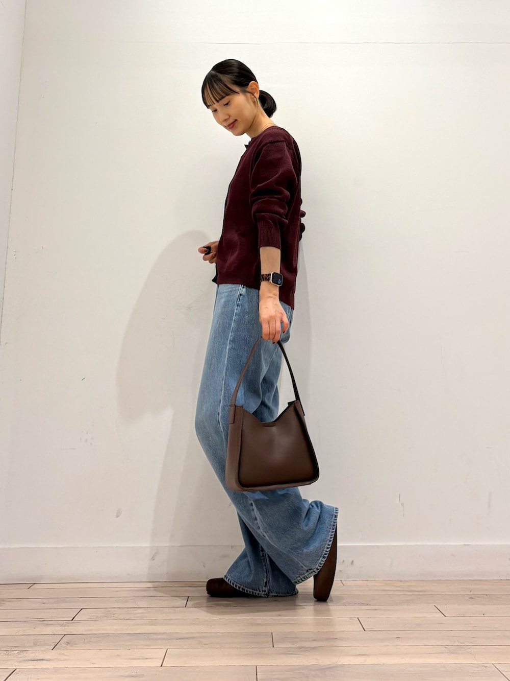 レッド系のカーディガン/ボレロ、ブルー系のデニムパンツ、ブラウン系のハンドバッグを着用したレディースの秋コーディネートの4枚目の写真
