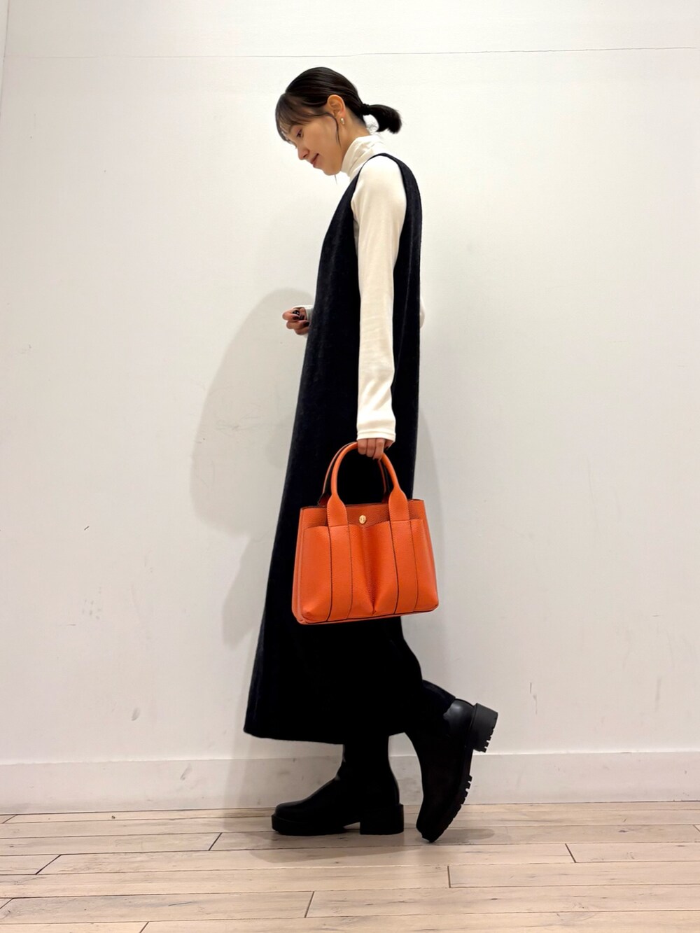 ブラック系のブーツ、オレンジ系のトートバッグ、グレー系のワンピースを着用したレディースの秋コーディネートの6枚目の写真