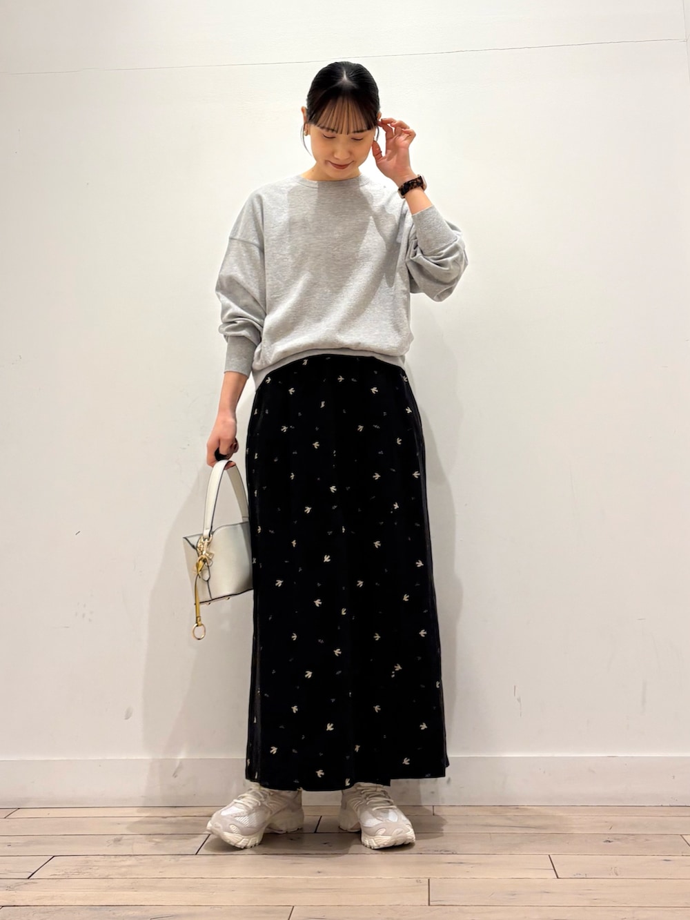 グレー系のTシャツ/カットソー、ブラック系のスカート、ホワイト系のショルダーバッグを着用したレディースの春コーディネートの2枚目の写真