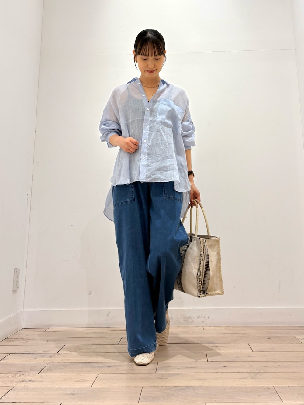 ブルー系のデニムパンツ、ホワイト系のトートバッグ、ホワイト系のバレエシューズを着用したレディースの夏コーディネートの2枚目の写真
