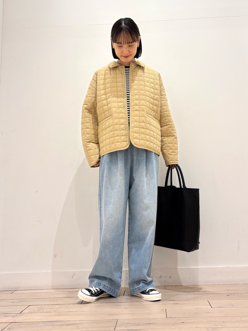 ホワイト系のTシャツ/カットソー、ベージュ系のダウンジャケット/コート、ブラック系のトートバッグを着用したレディースの冬コーディネートの2枚目の写真