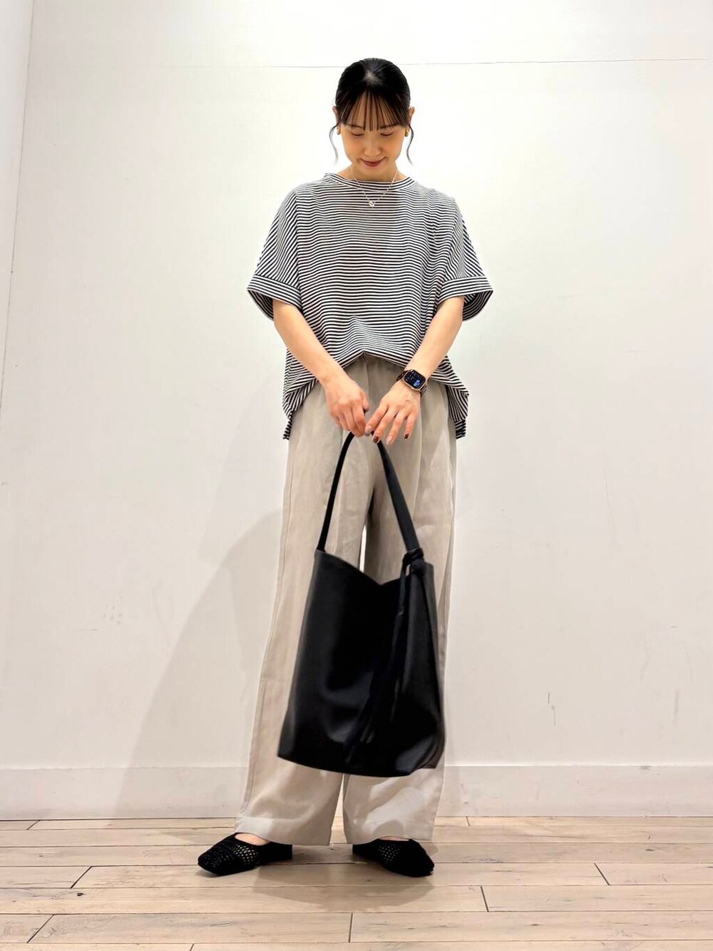 ブラック系のトートバッグ、ブラック系のバレエシューズ、ホワイト系のTシャツ/カットソーを着用したレディースの夏コーディネートの2枚目の写真